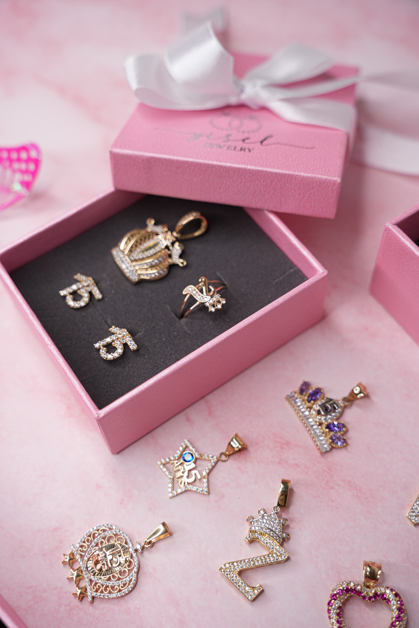 Caja de regalo rosa con dijes de quinceañera en oro y diamantes