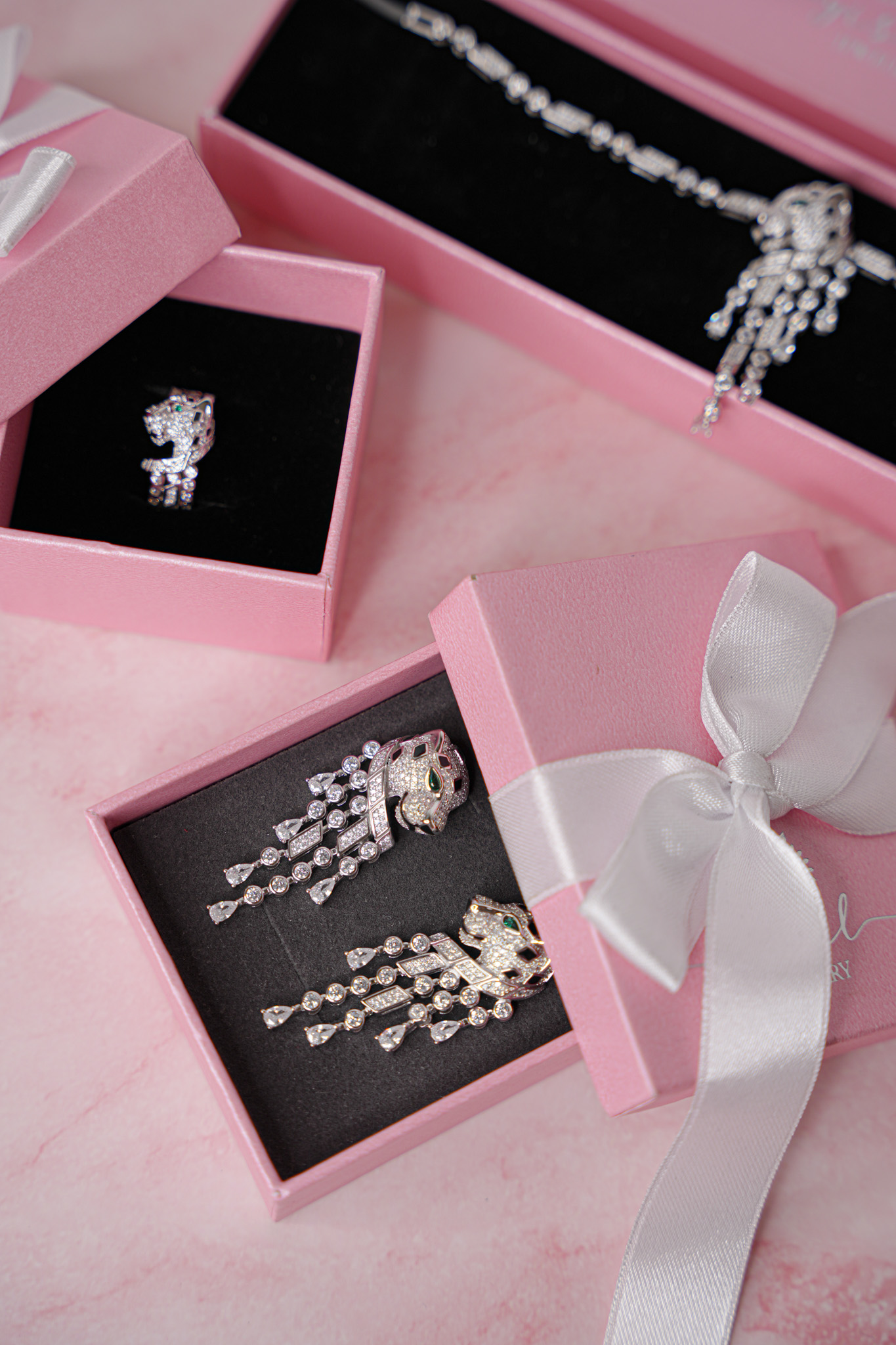 Aretes y anillo de diamantes en cajas de regalo rosas con lazo blanco